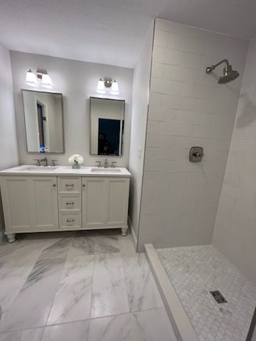 A bathroom with two sinks and a walk in shower.