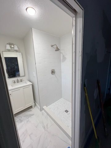 A bathroom with a walk in shower , sink and mirror.