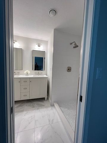 A bathroom with two sinks and a walk in shower.
