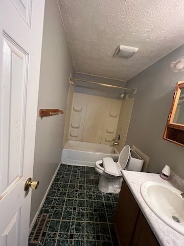 A bathroom with a toilet , sink , bathtub and mirror.
