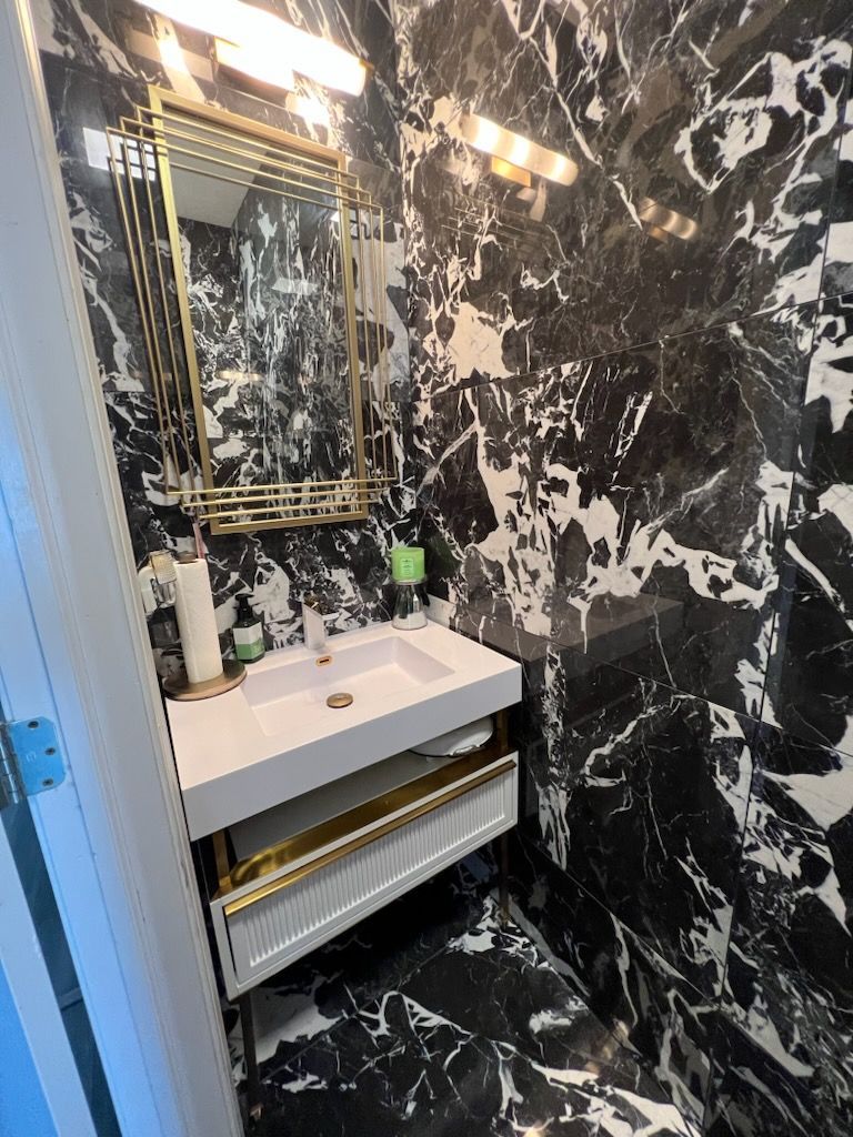 A bathroom with a sink , mirror , and black and white tiles.