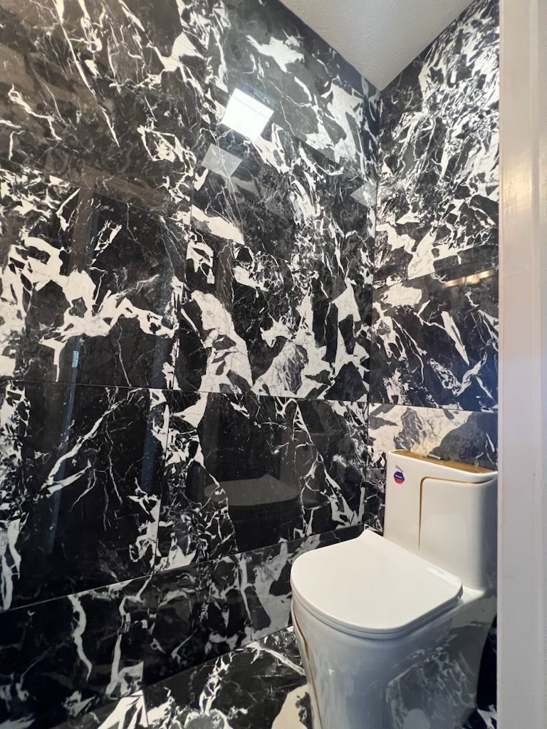 A bathroom with black and white marble walls and a toilet.