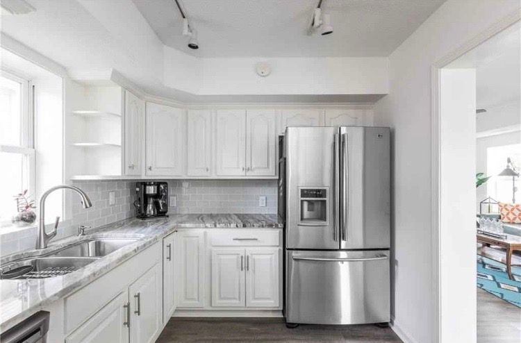 A kitchen with white cabinets and a stainless steel refrigerator.