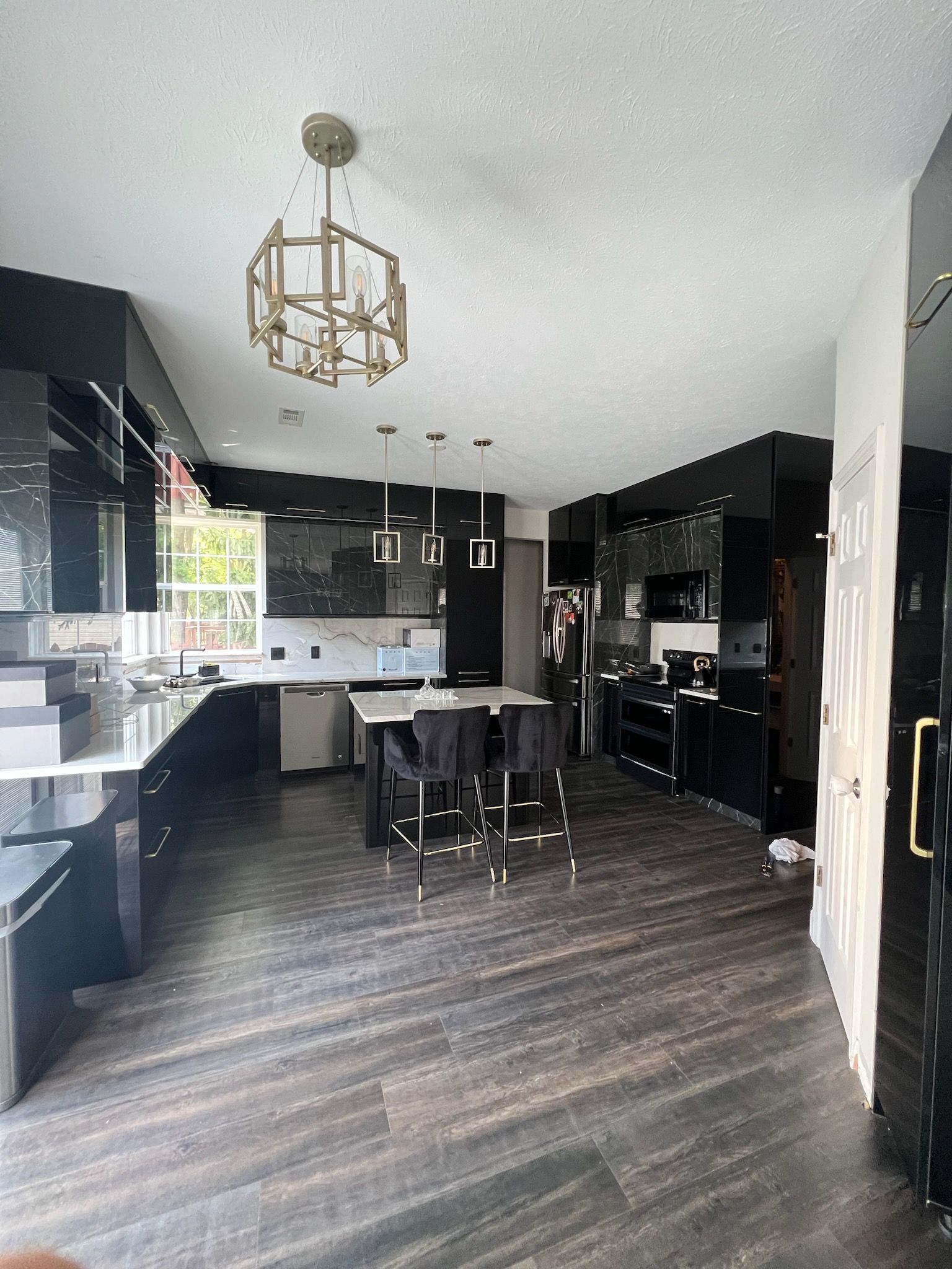 A large kitchen with black cabinets and a chandelier hanging from the ceiling.