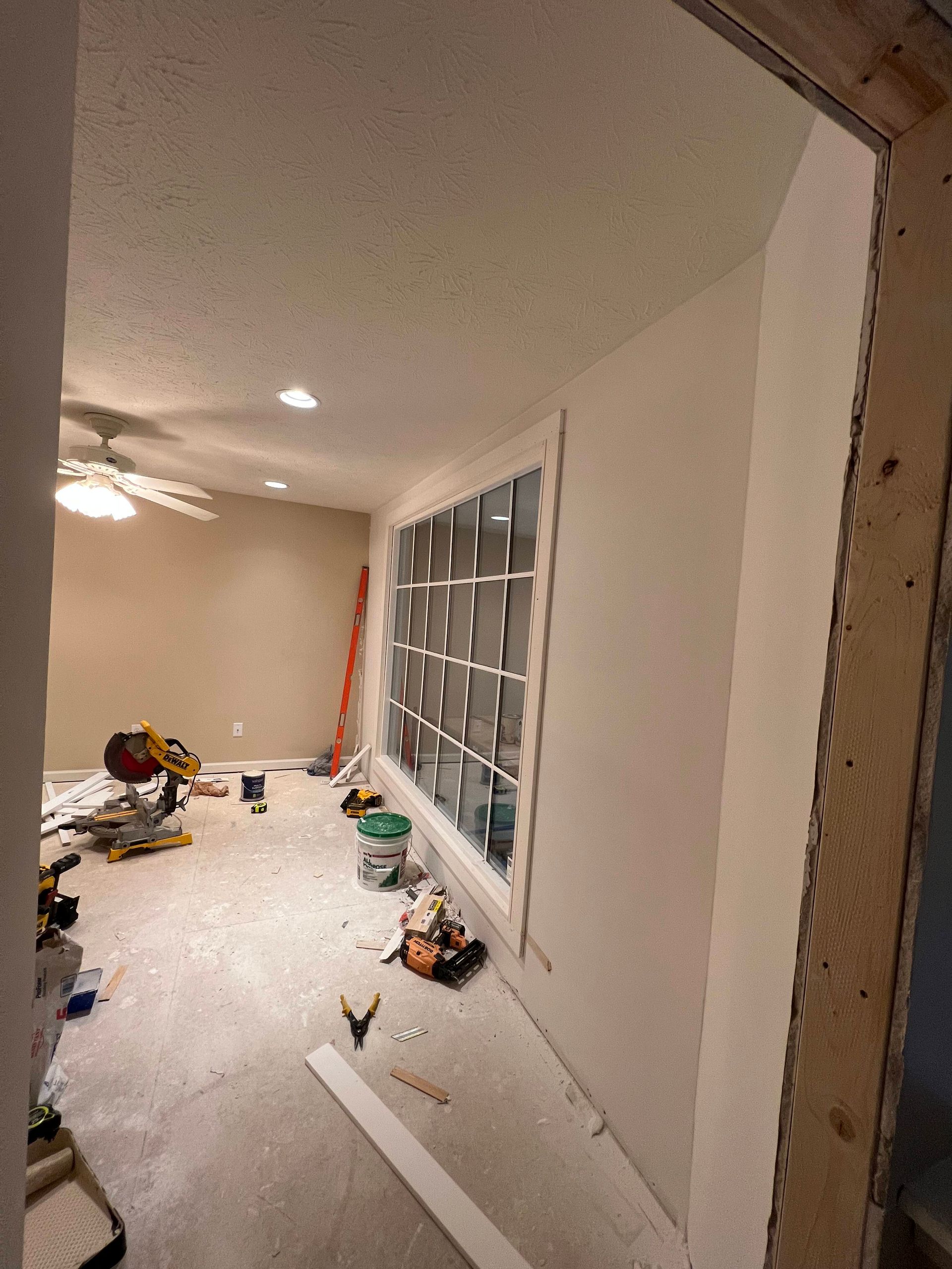 A room is being remodeled with a large window and a ceiling fan.