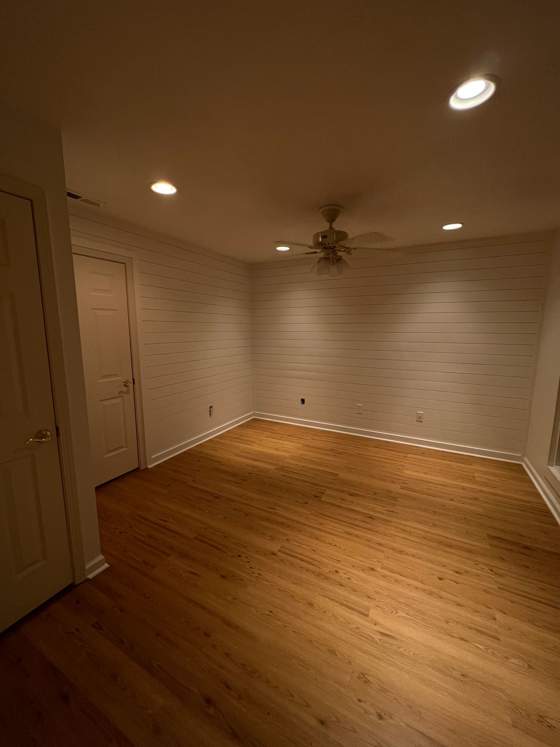 An empty room with hardwood floors and a ceiling fan.