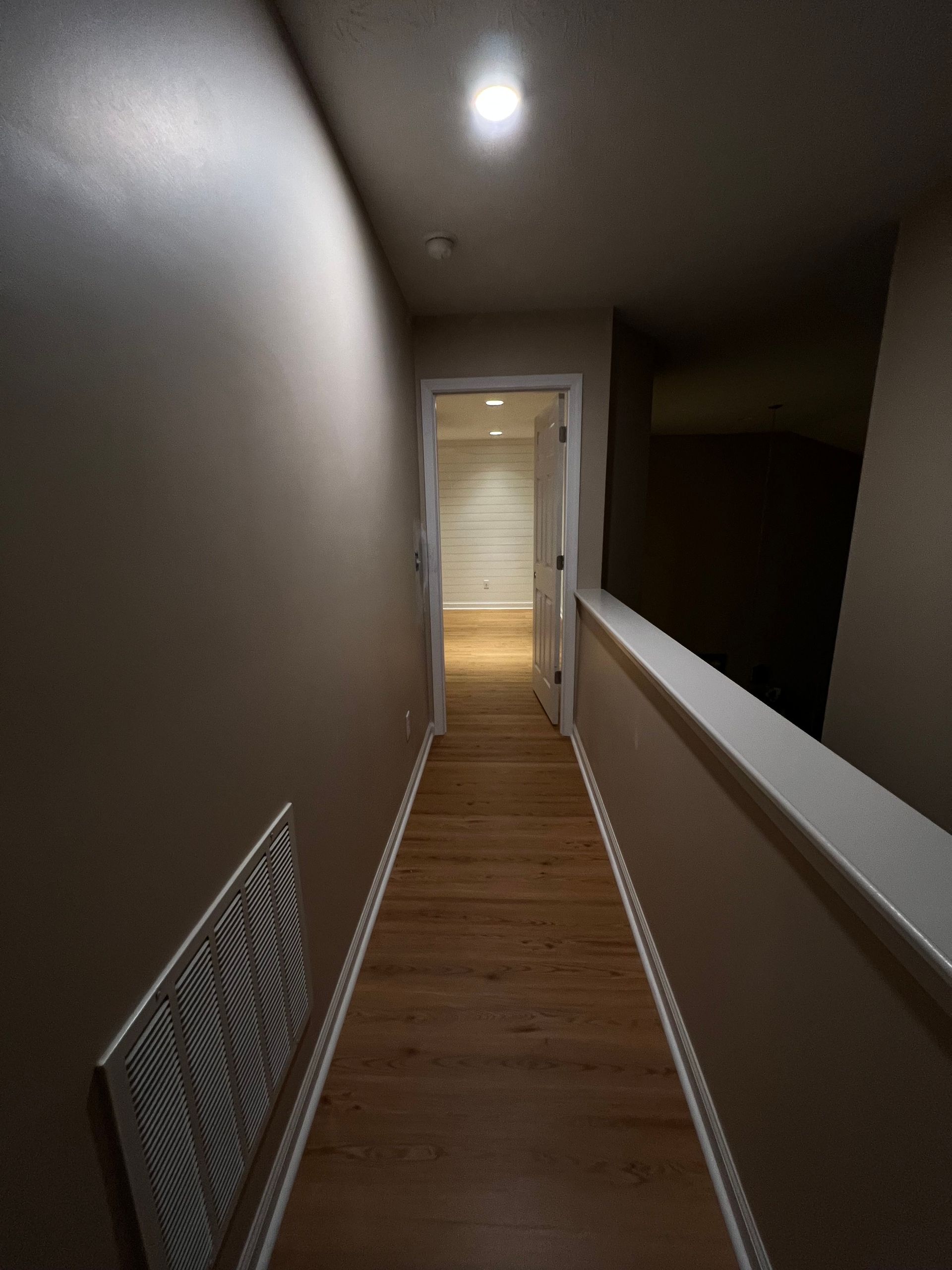 A hallway with a wooden floor and a white door
