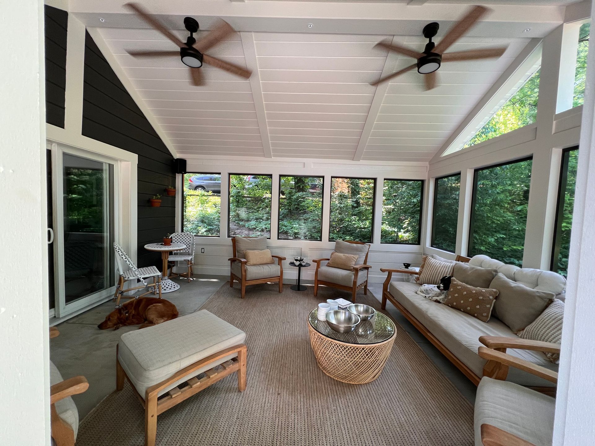 A living room with a couch , chairs , a table and a dog.