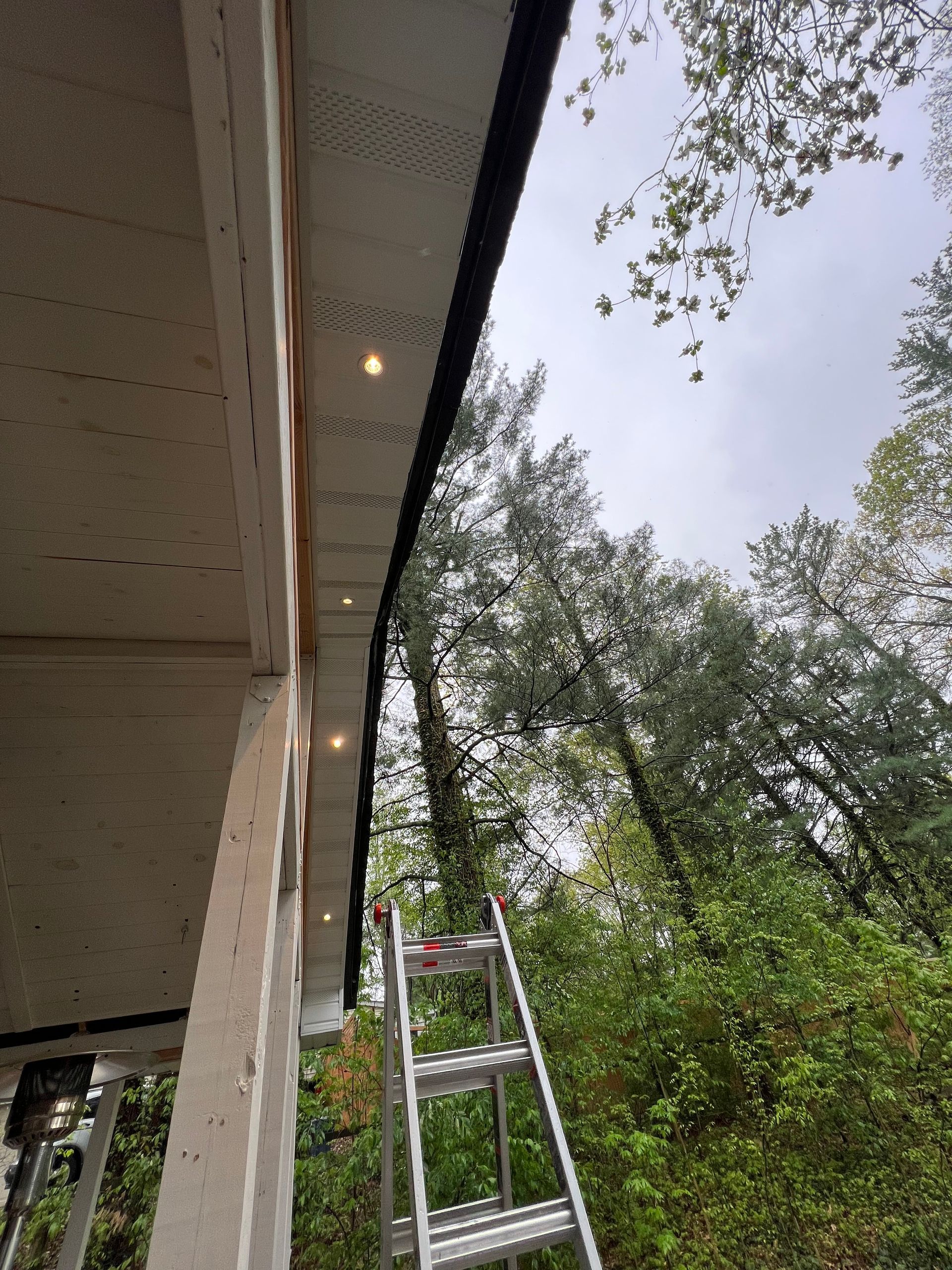A person is standing on a ladder under a roof.