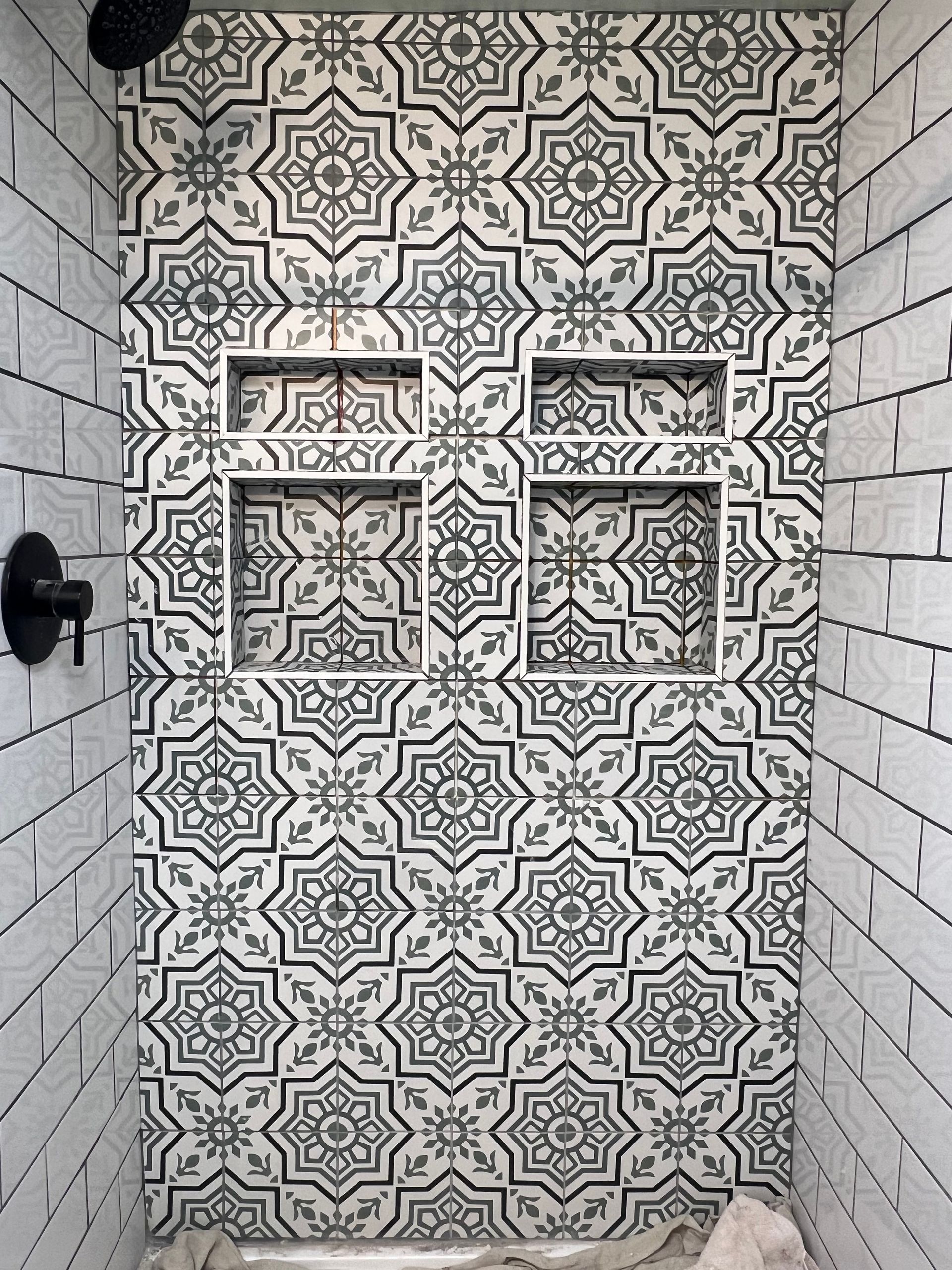 A shower with black and white tiles and a shower head.