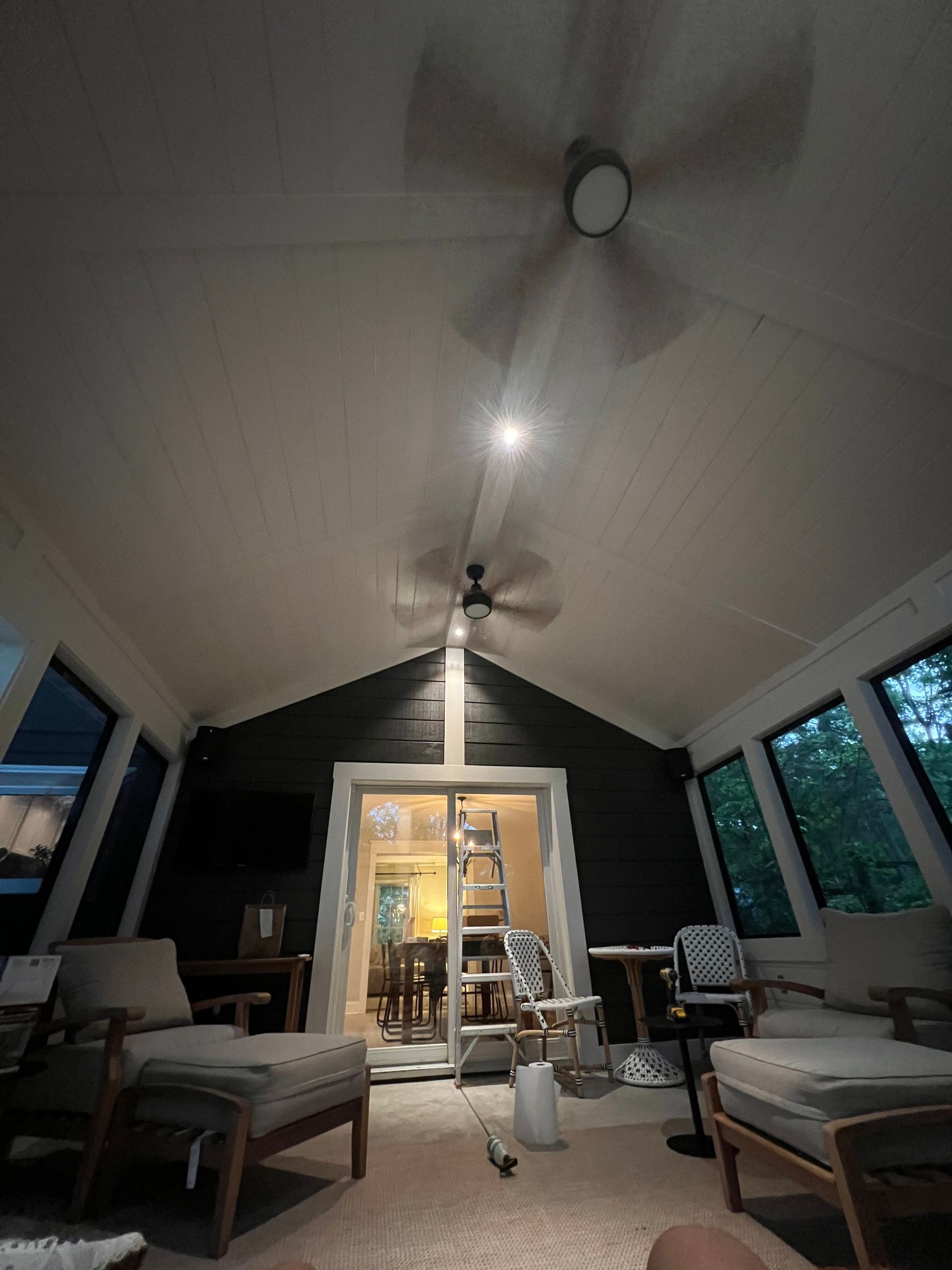 A living room with a ceiling fan and a ladder