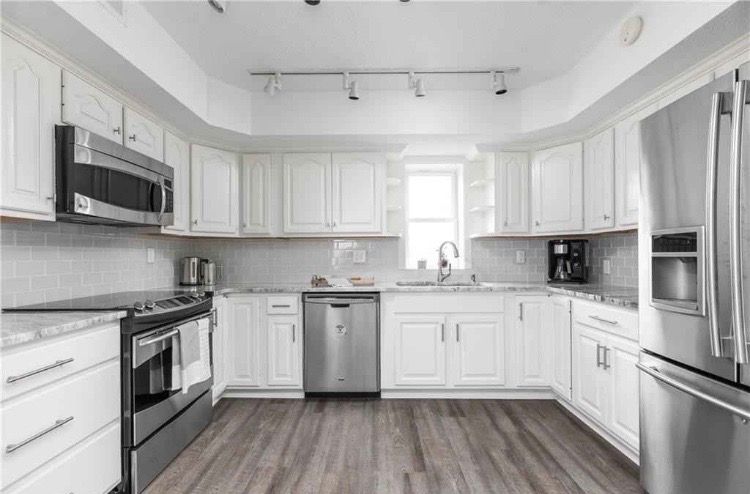 A kitchen with white cabinets and stainless steel appliances