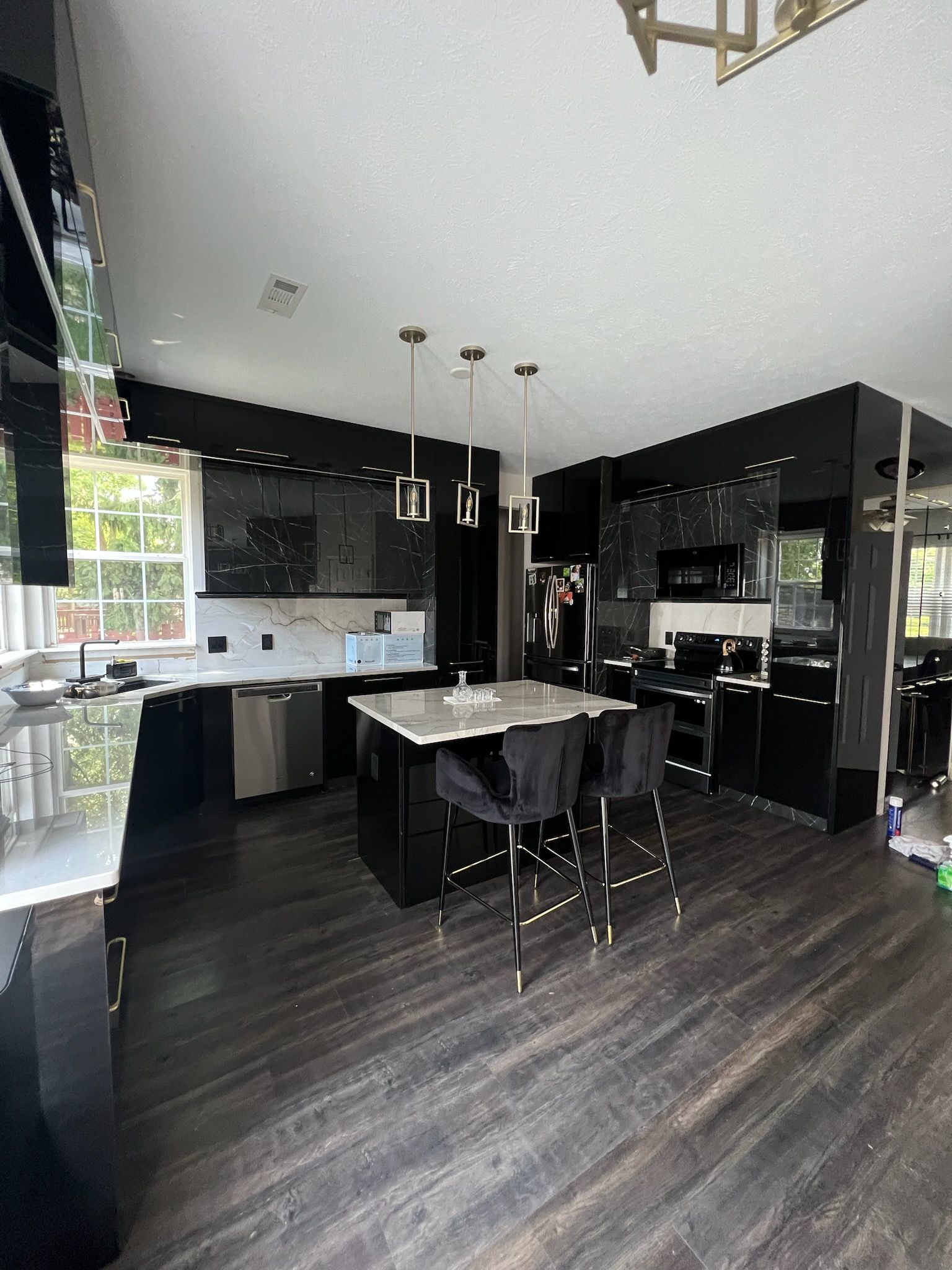 A kitchen with black cabinets and a large island in the middle.