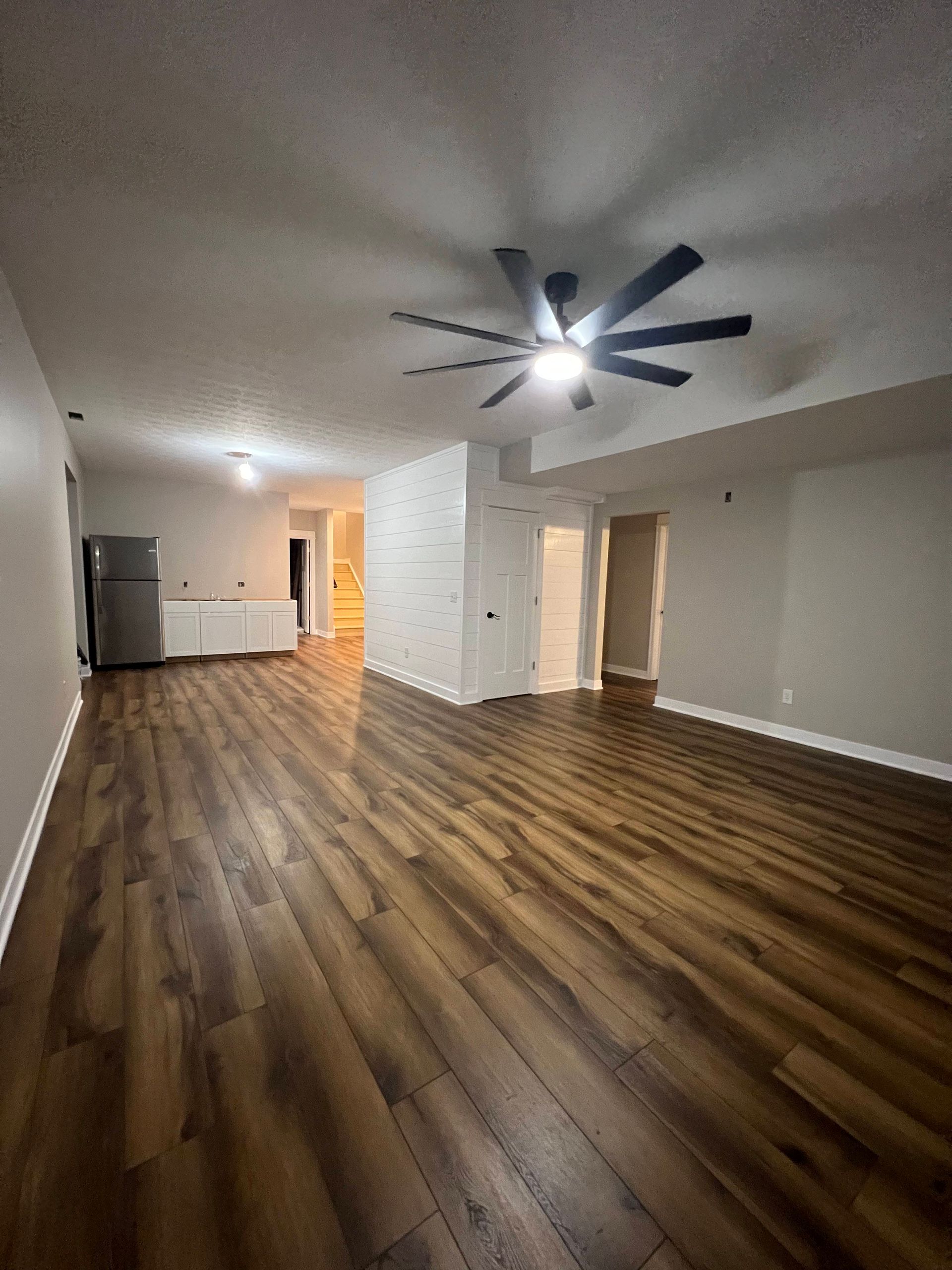 An empty living room with hardwood floors and a ceiling fan.