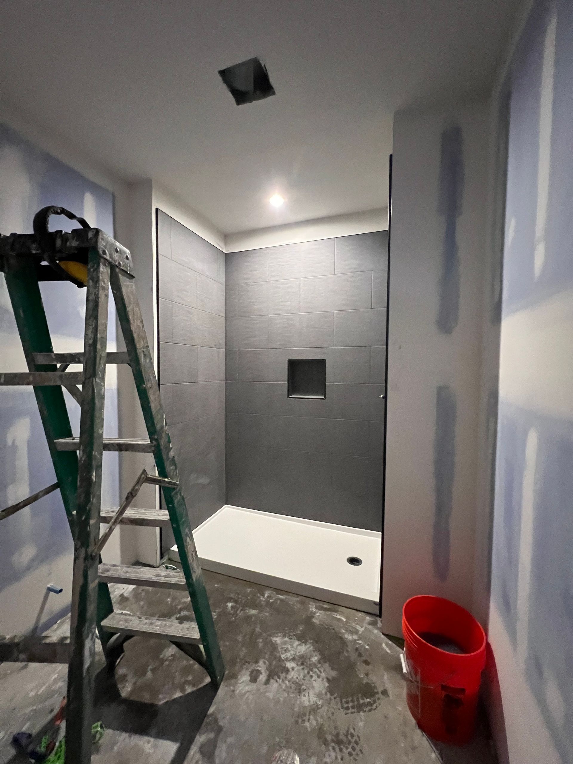 A bathroom under construction with a ladder and a red bucket.