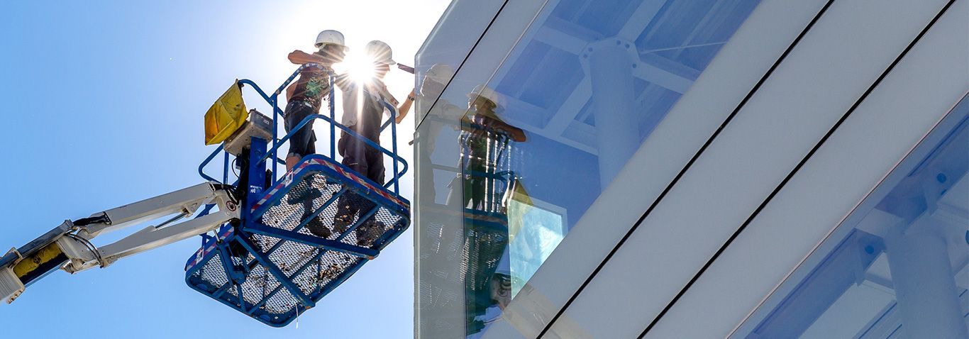 DEV Builders' workers are cleaning the windows of a building.
