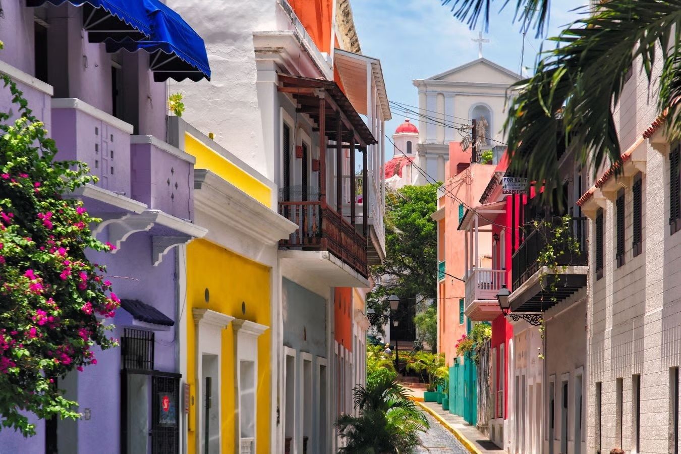 Colorful street lined with buildings in Old San Juan, Puerto Rico. Buildings have balconies and brightly painted facades.