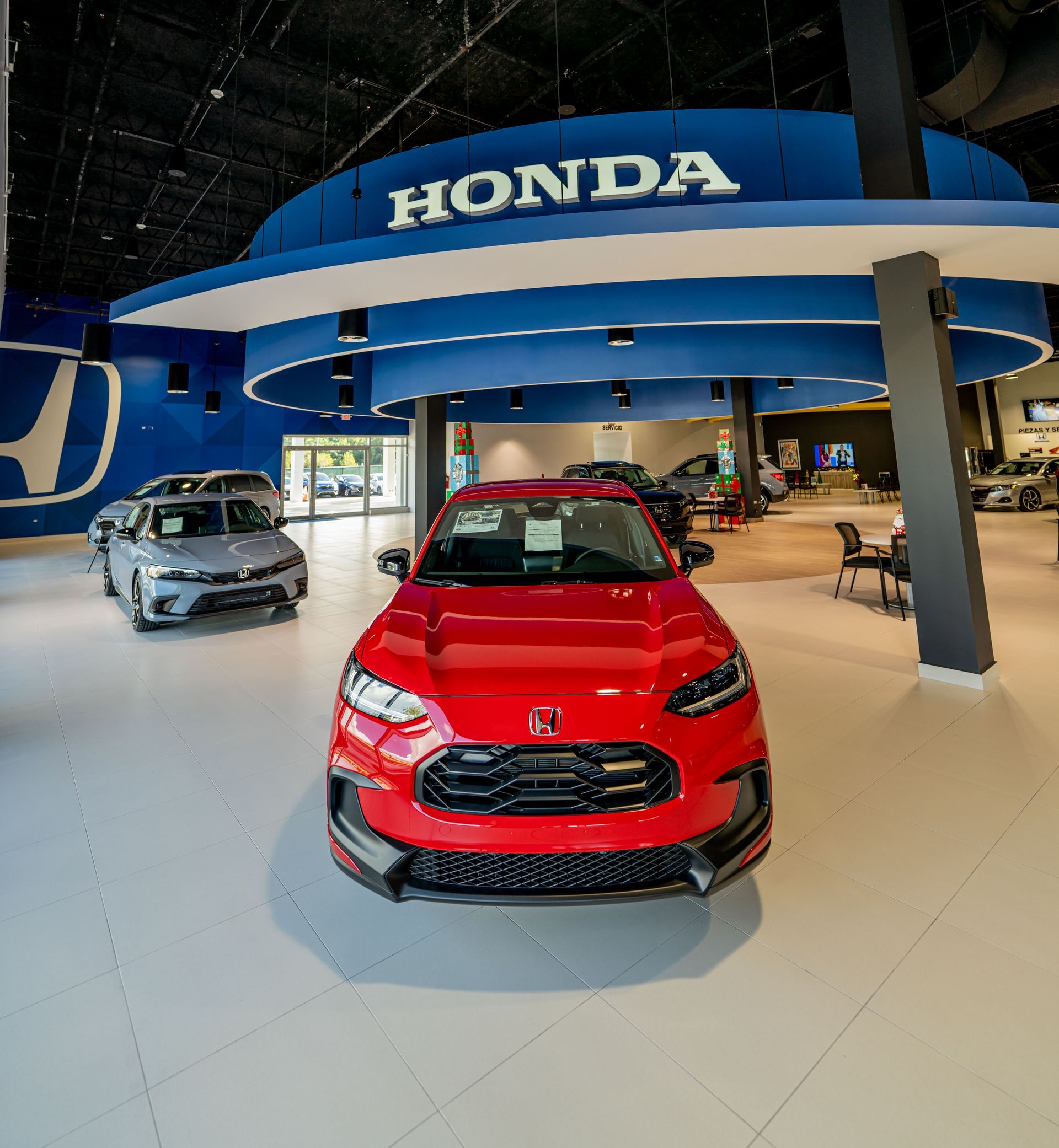 A red honda car is parked in a honda showroom designed and built by DEV Builders.