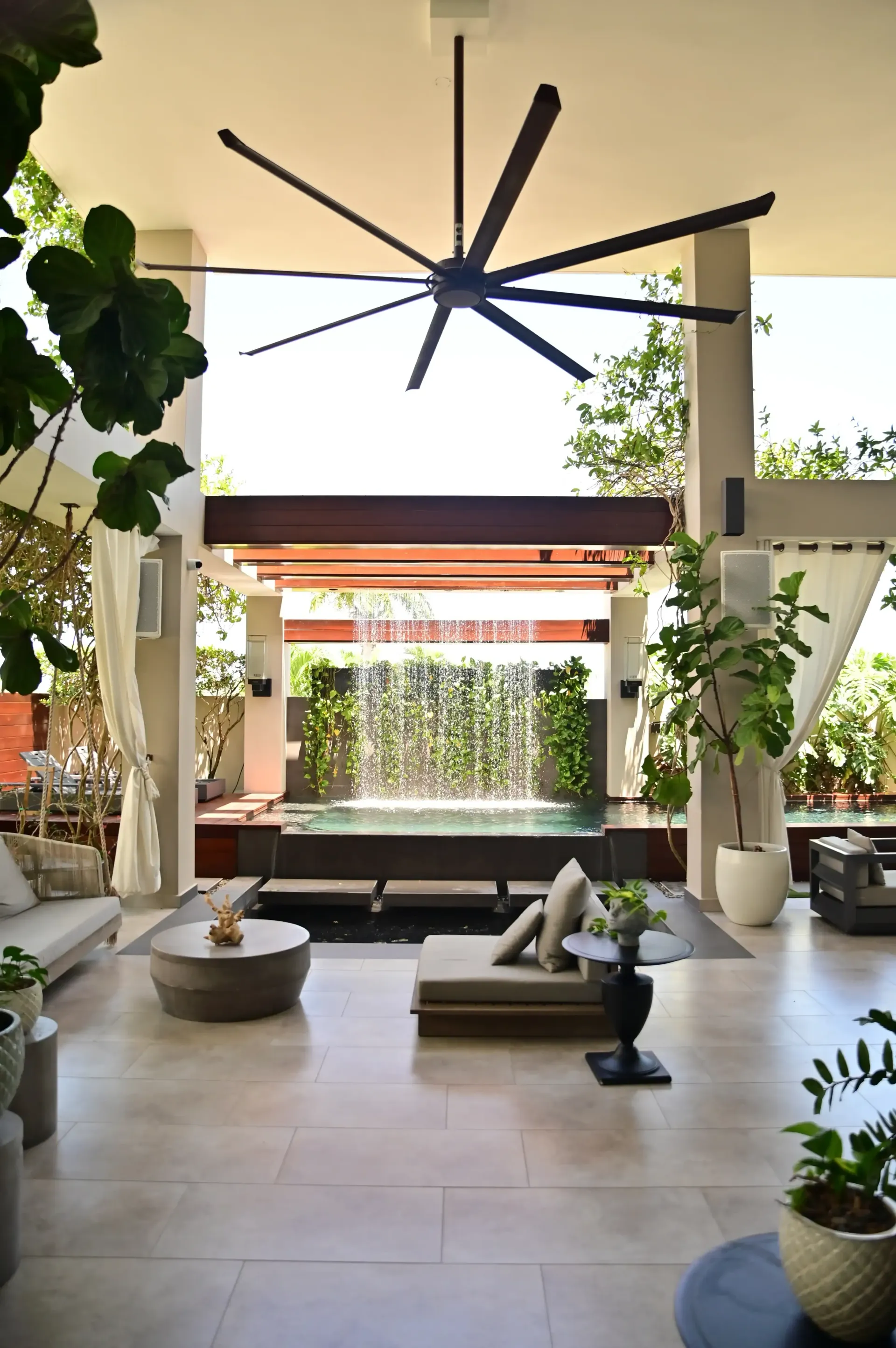 A living room with a ceiling fan and a waterfall in the background built by DEV Builders