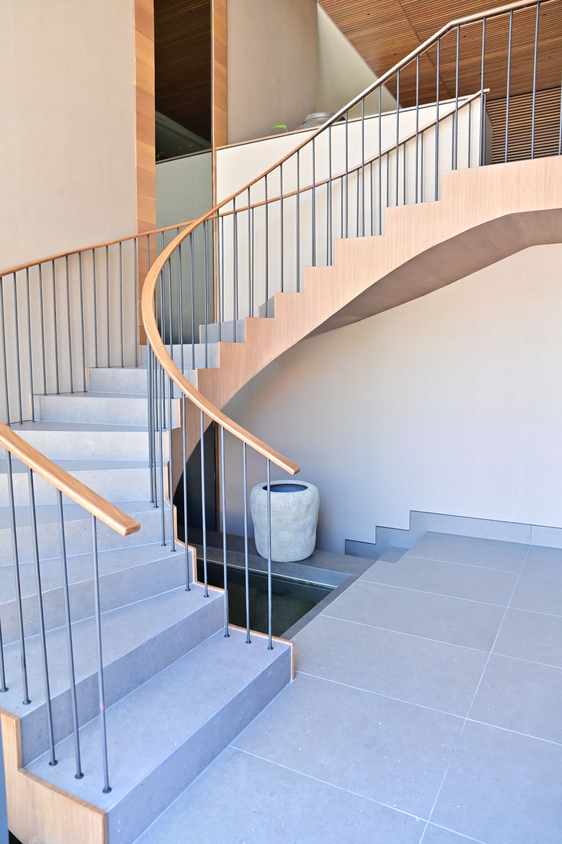 A curved staircase with a metal railing in a building designed and built by DEV Builders