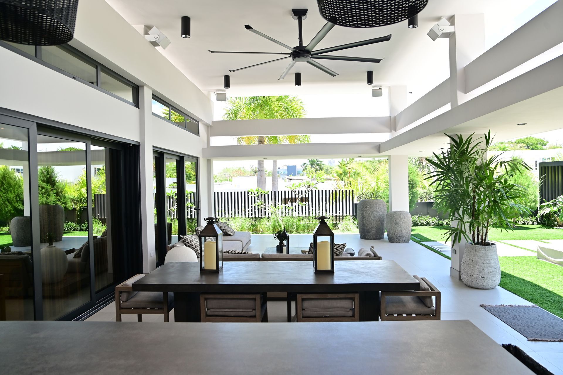 A large exterior room with a table and chairs and a ceiling fan designed by DEV Builders