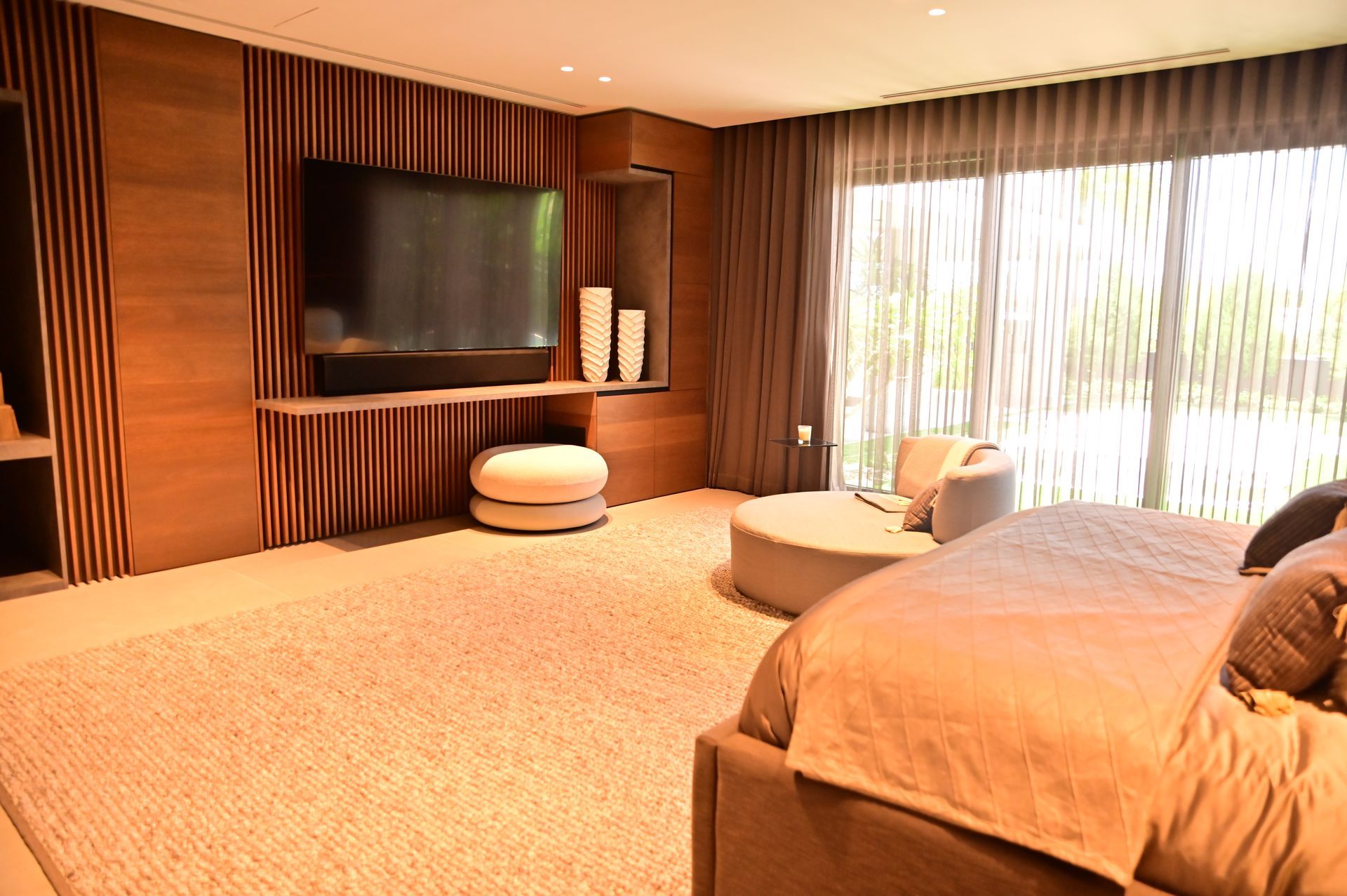 A bedroom with a bed , couch , television and sliding glass doors designed and built by DEV Builders.