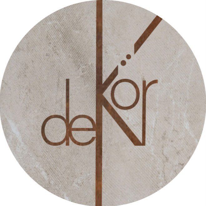 Circular logo with "deKör" text in rust-brown. A central vertical line and diagonal line with dots also in rust-brown. Background is textured beige.