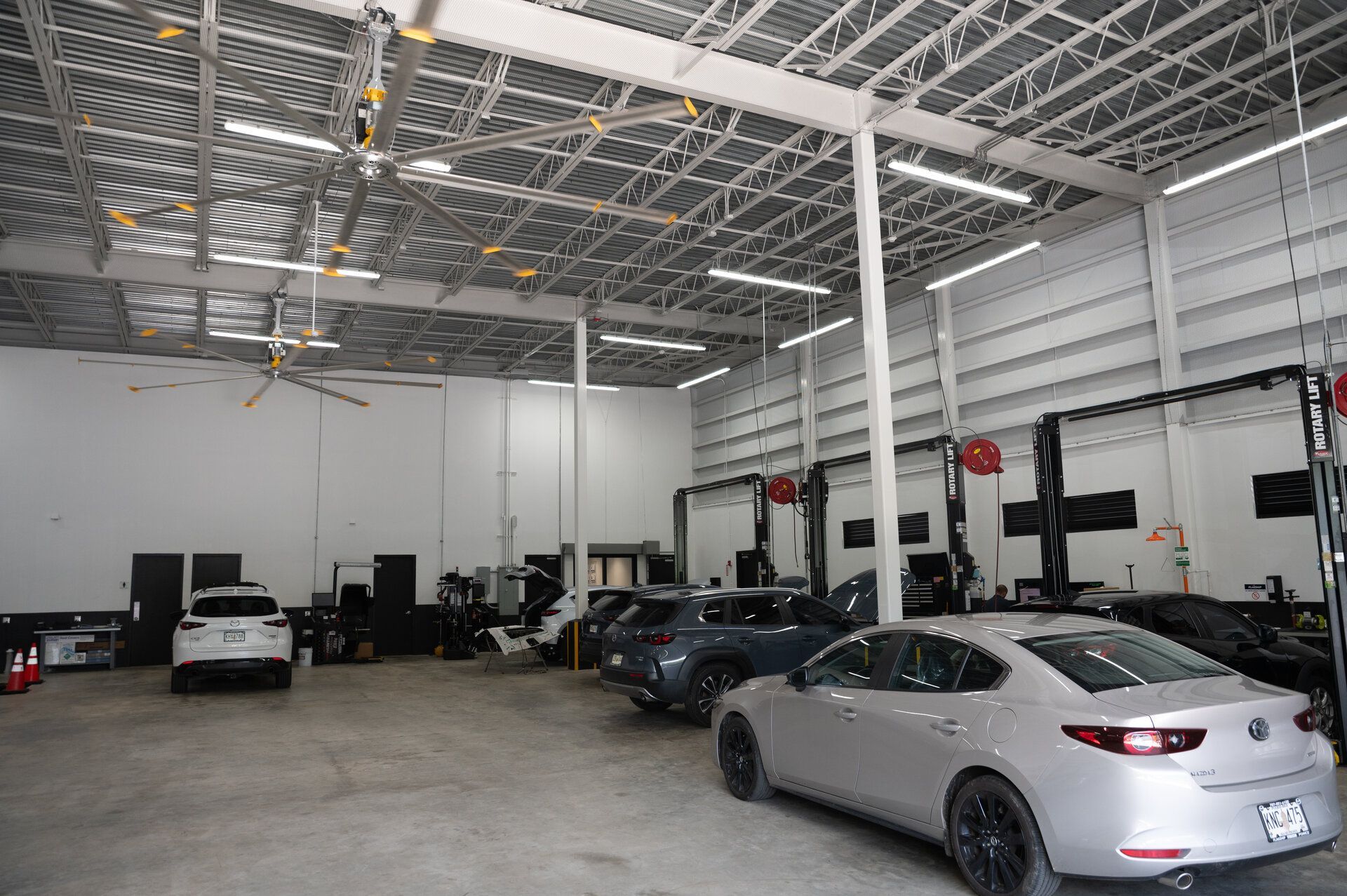 Cars inside a well-lit auto repair shop with tall ceilings and vehicle lifts in Puerto Rico.