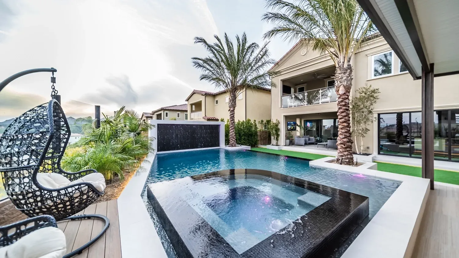 Luxury swimming pool and tile spa in large backyard and outdoor living space.