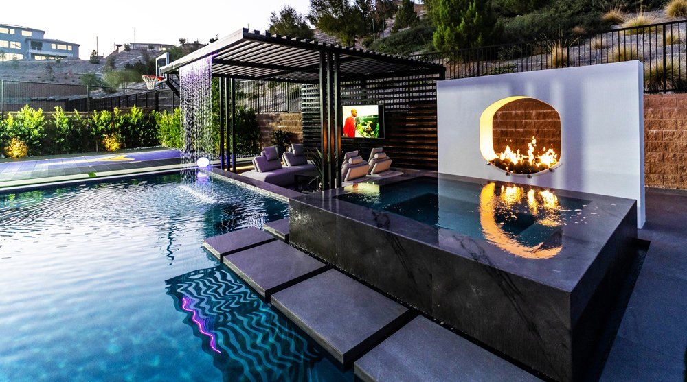 Custom swimming pool featuring a spa, fire features, sunken lounge area, rain descent, and basketball hoop. Pool project designed and built by Westmod.