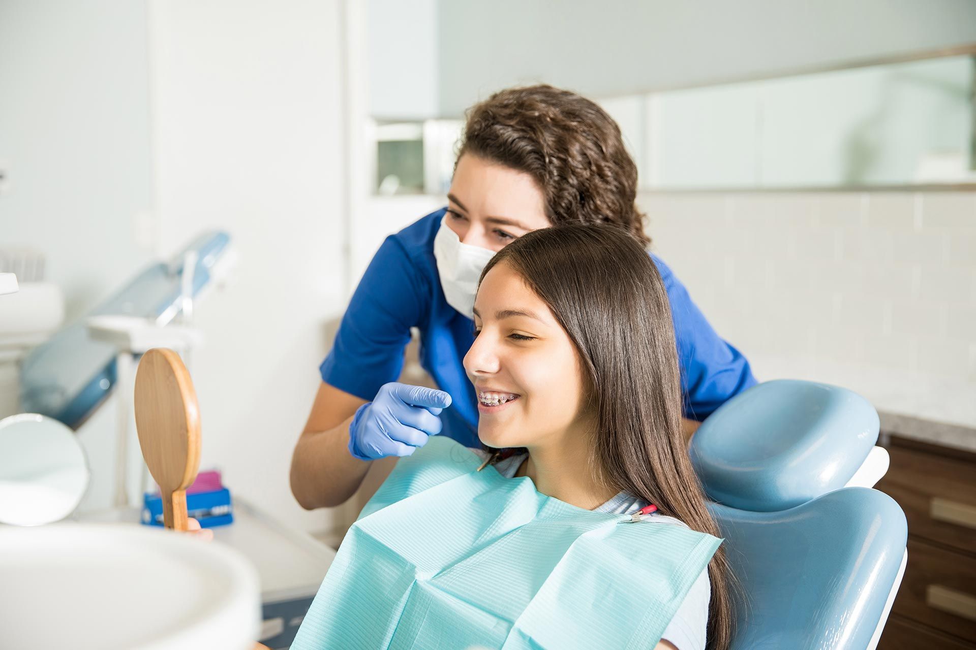 Teen girl smiling with new braces at orthodontist appointment with dental hygienist.