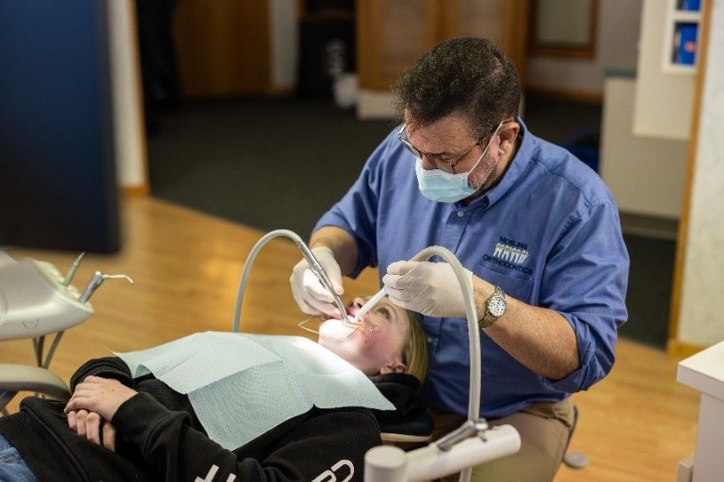 Dental professional checking a patient’s smile with a mirror during a clinic visit.