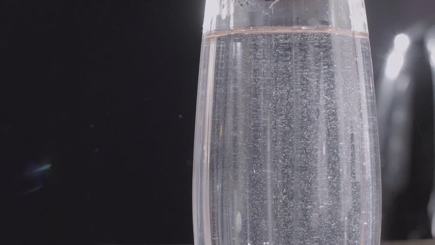 A glass of water is being poured into a glass on a table.