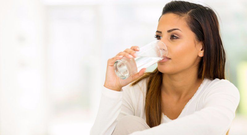 A woman is drinking a glass of water.