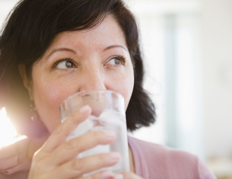 A woman is drinking a glass of water.