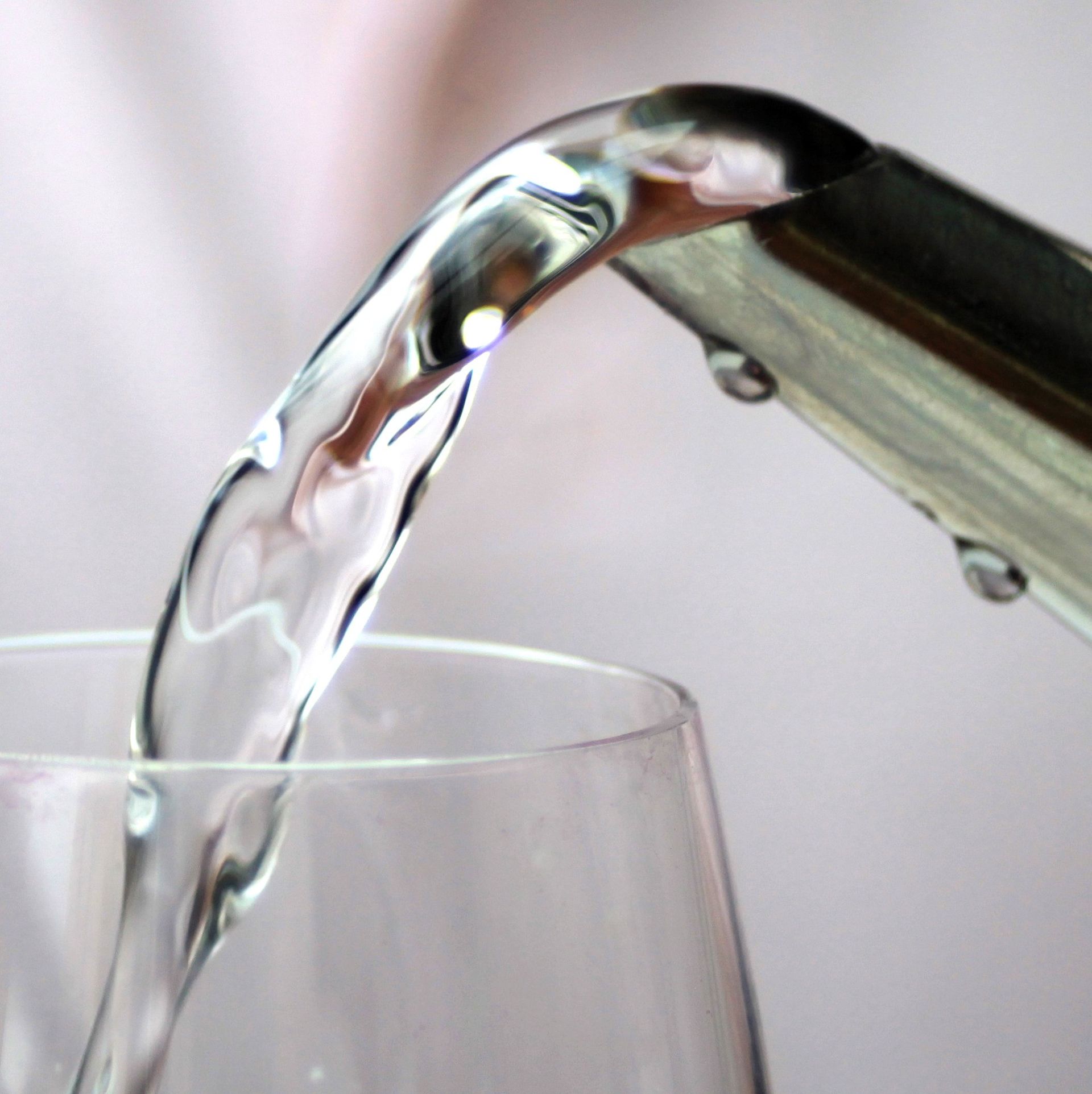 Water is being poured into a glass from a faucet