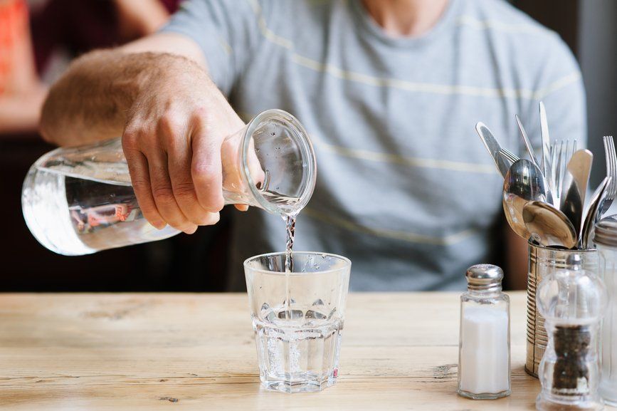 A man is pouring water from a bottle into a glass.