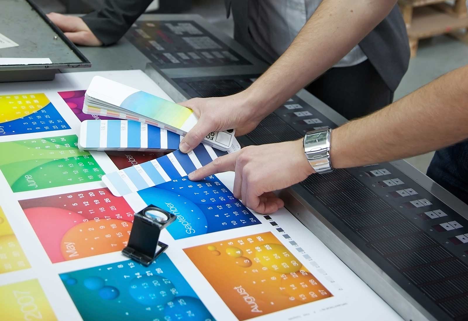 A man wearing a watch is pointing at a palette of colors