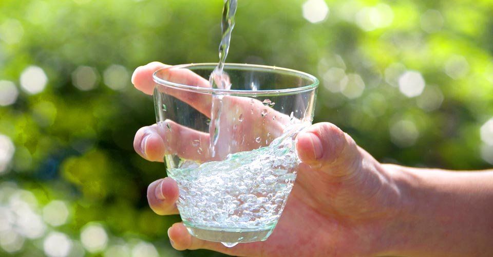 A person is pouring water into a glass.