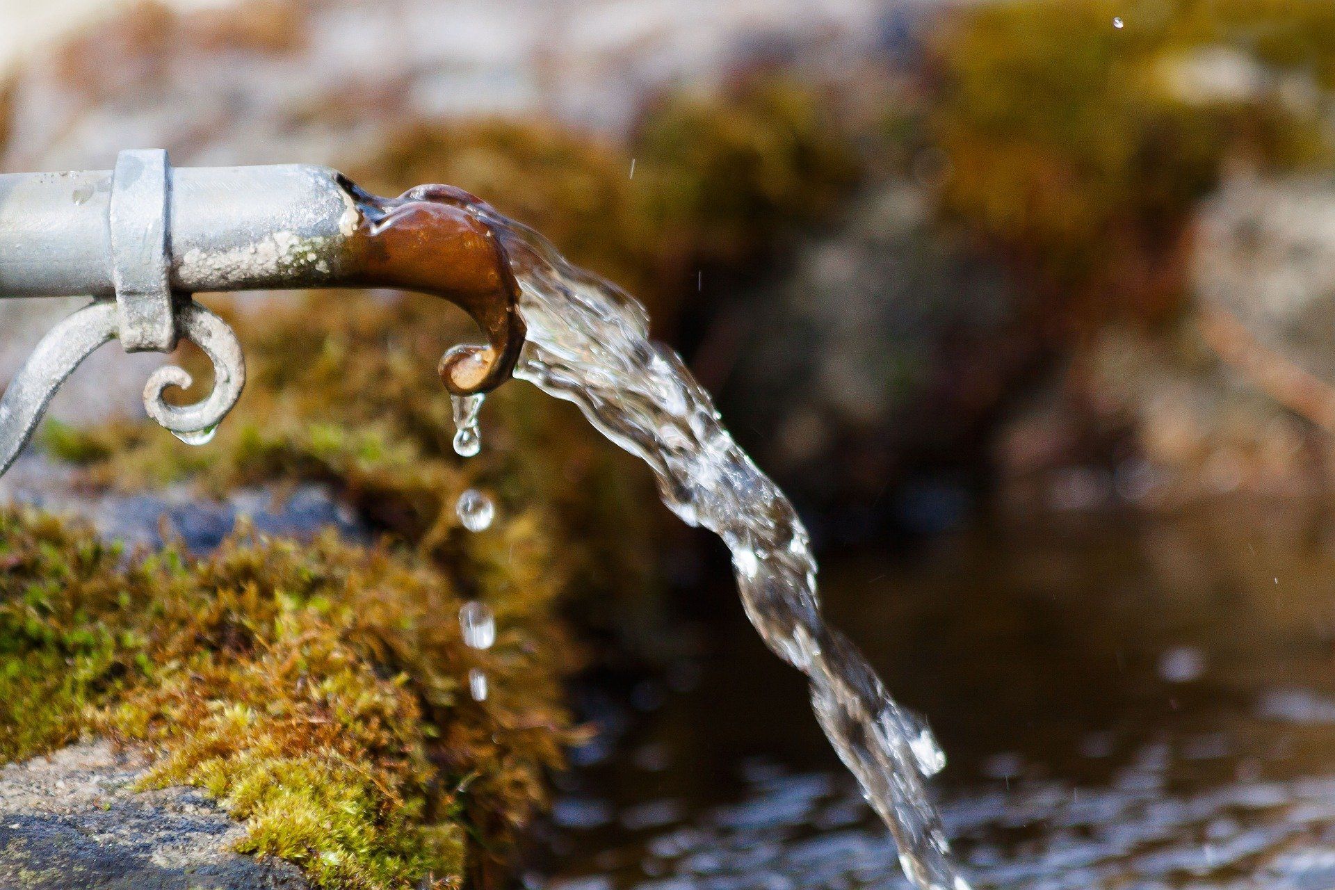 Water is coming out of a faucet on a rock.