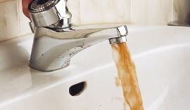 Brown water is coming out of a faucet into a sink.