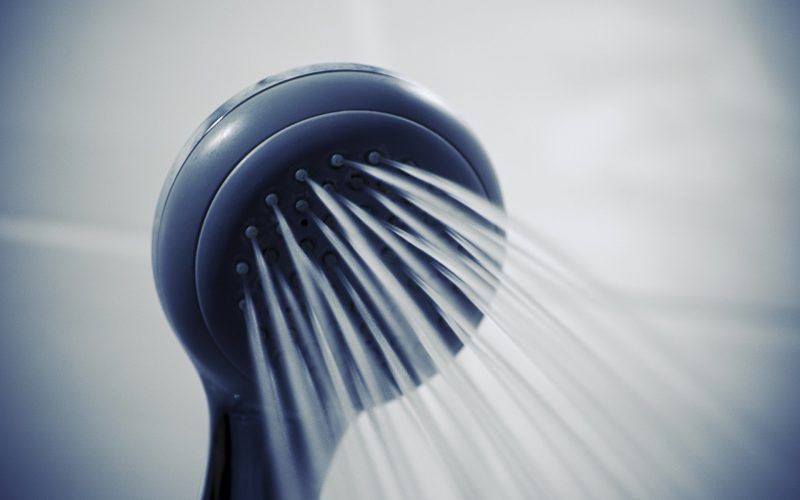 A close up of a shower head with water coming out of it