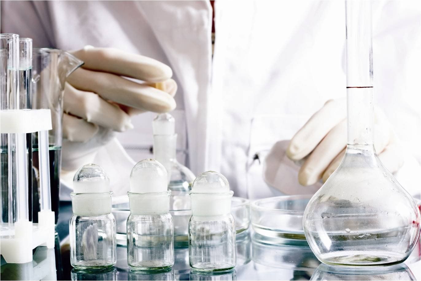 A scientist is using a beaker to pour liquid into a test tube.