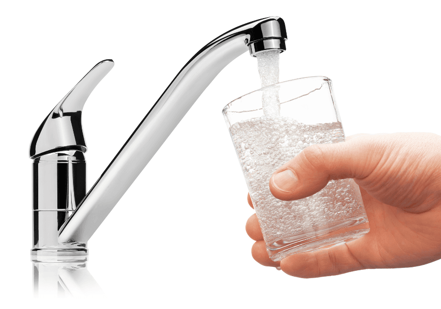 A glass of water is being poured from a faucet