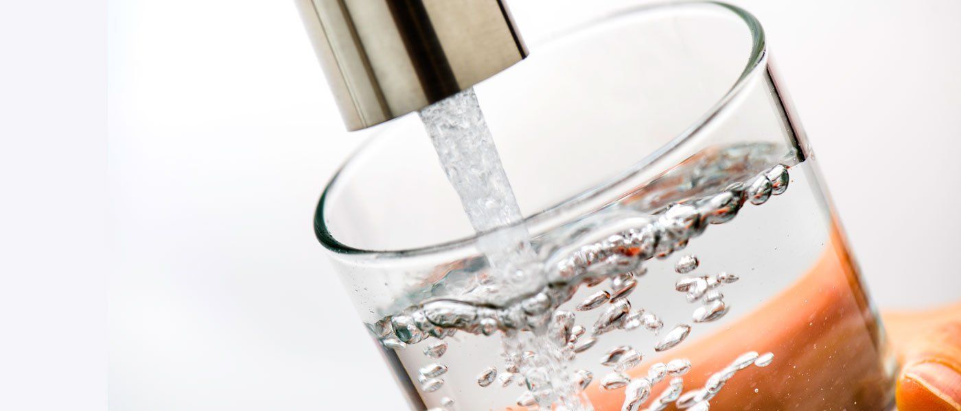 Water is being poured into a glass from a faucet.