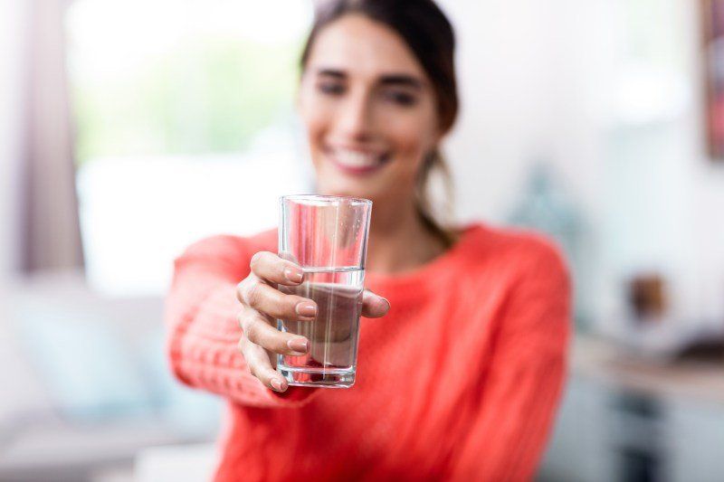 A woman is holding a glass of water in her hand.