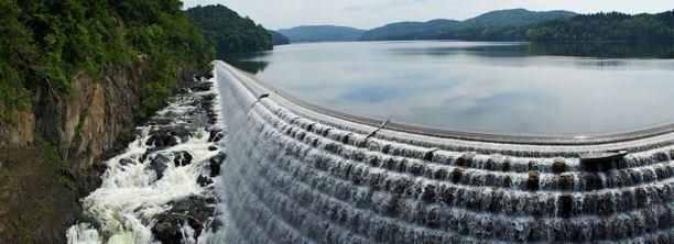 A large waterfall is coming down a dam into a lake.