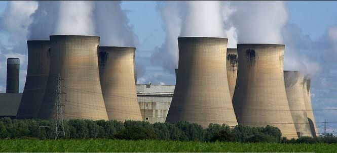 A nuclear power plant with smoke coming out of the cooling towers.