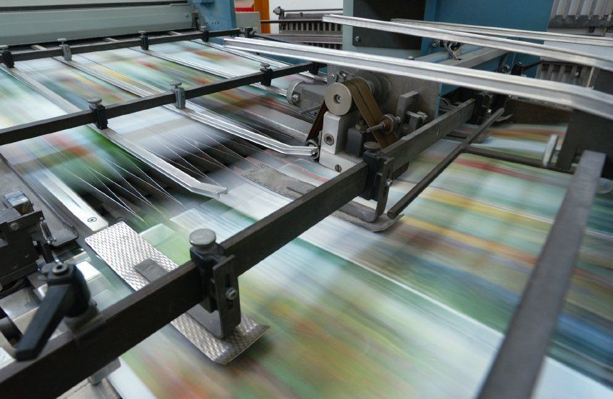 A machine is printing a lot of papers on a conveyor belt