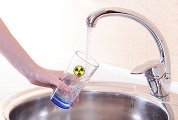 A person is pouring water into a glass in a sink.